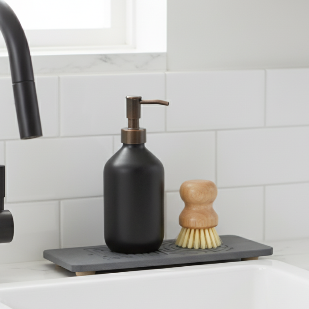 Black soap dispenser and wooden brush on a gray dish drying rack in a kitchen.