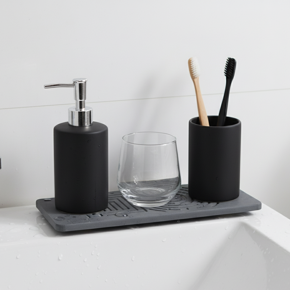 Bathroom counter with black soap dispenser, glass, and toothbrush holder with toothbrushes - countertop protector mat